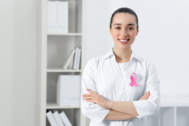 Photo of Mammologist with pink ribbon in hospital, space for text. Breast cancer awareness