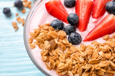 Photo of Bowl with yogurt, berries and granola on table, closeup