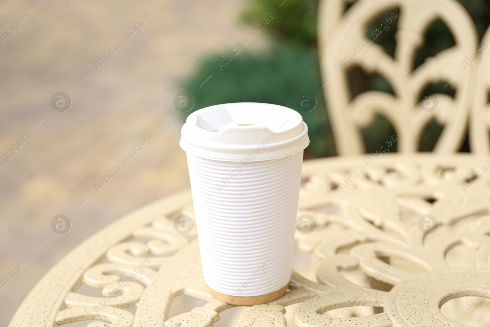 Photo of Paper cup of coffee on table outdoors. Takeaway drink