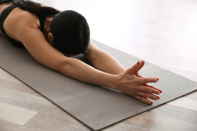 Young woman practicing extended child's asana in yoga studio, closeup. Utthita Balasana pose