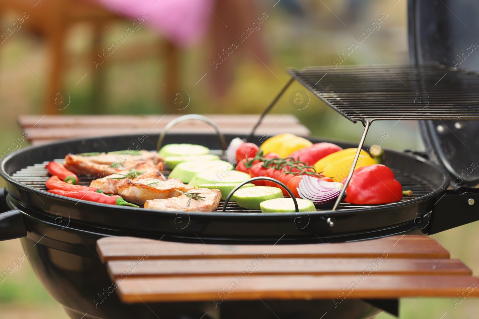 Photo of Modern grill with meat and vegetables outdoors, closeup