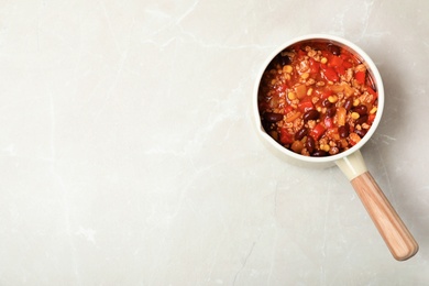 Photo of Saucepan with chili con carne and space for text on light background, top view