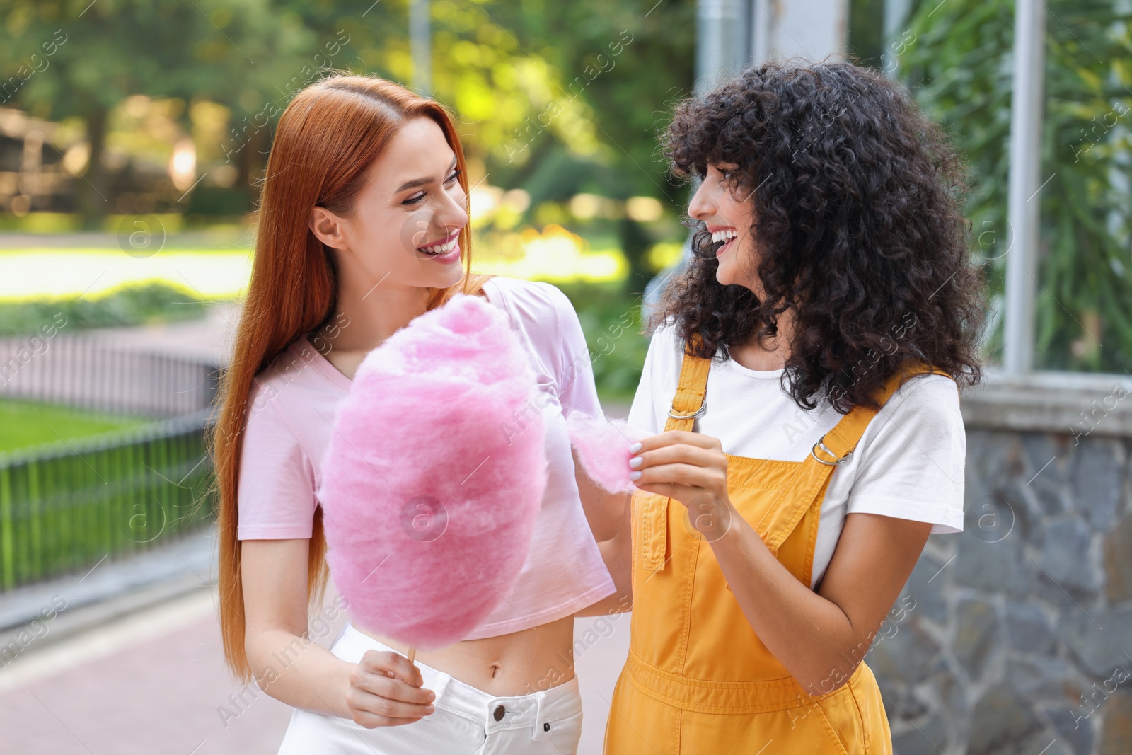 Photo of Happy friends with cotton candy spending time together in park