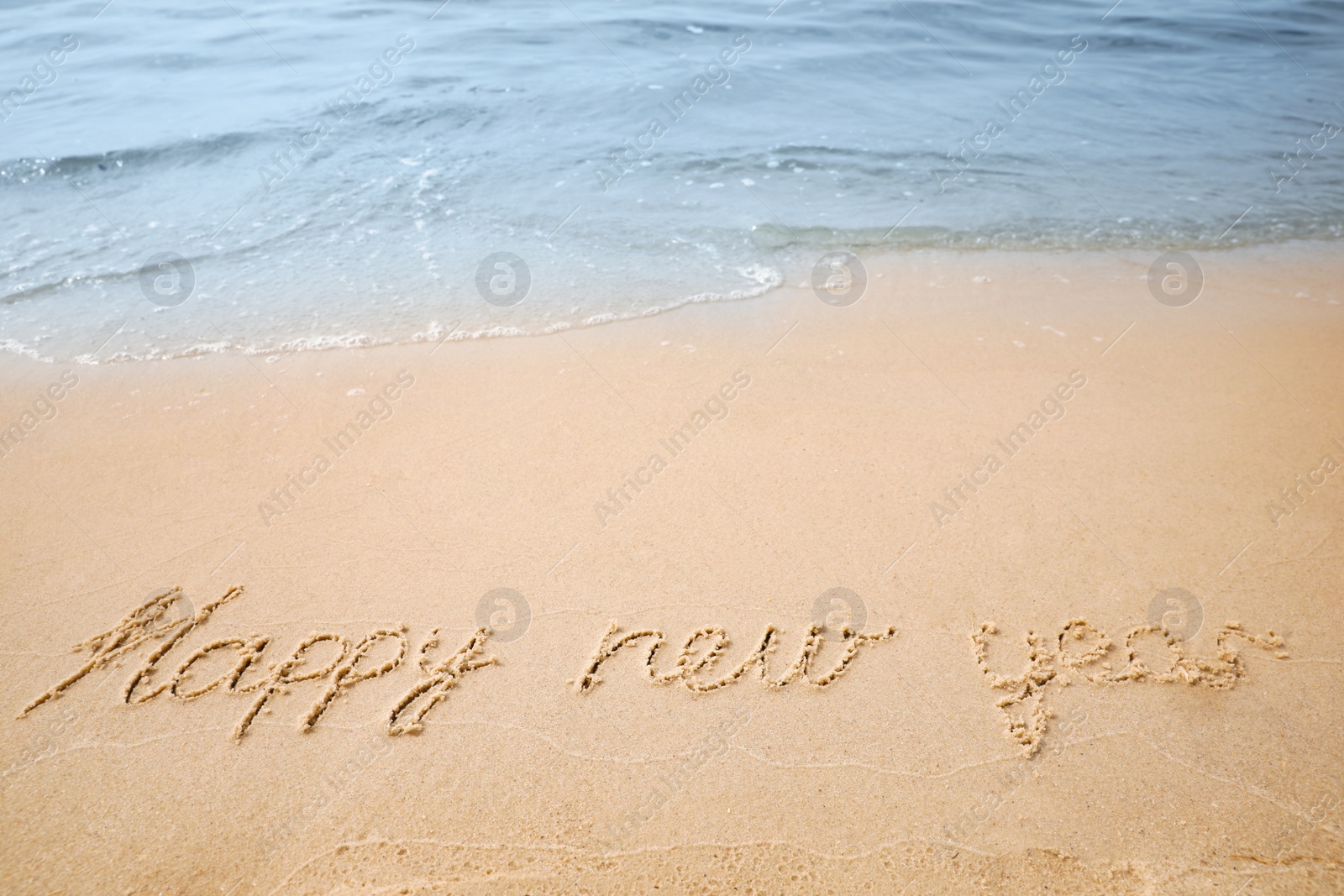 Photo of Sandy beach with text Happy New Year washed by sea