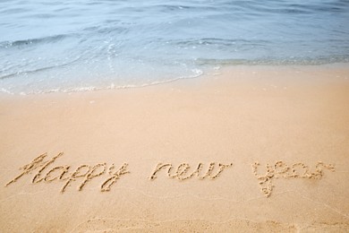 Photo of Sandy beach with text Happy New Year washed by sea