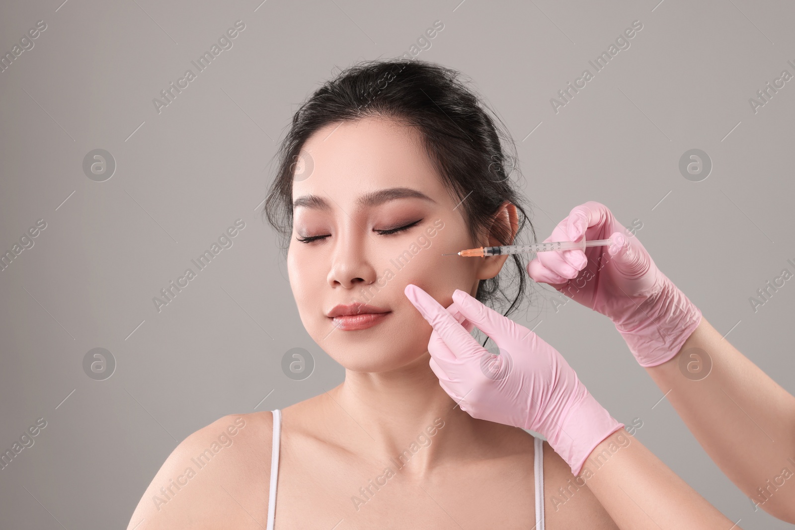 Photo of Woman getting facial injection on grey background