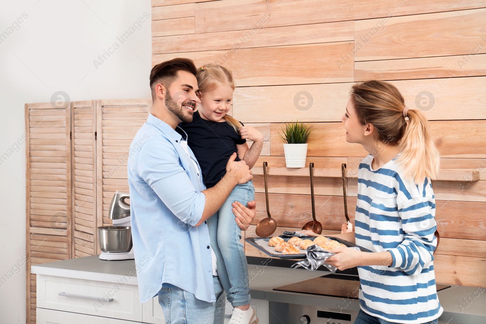 Photo of Young woman treating her family with homemade oven baked cookies in kitchen