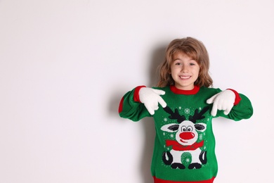 Photo of Cute little girl pointing at her green Christmas sweater against white background