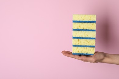 Photo of Woman holding sponges on pink background, closeup. Space for text