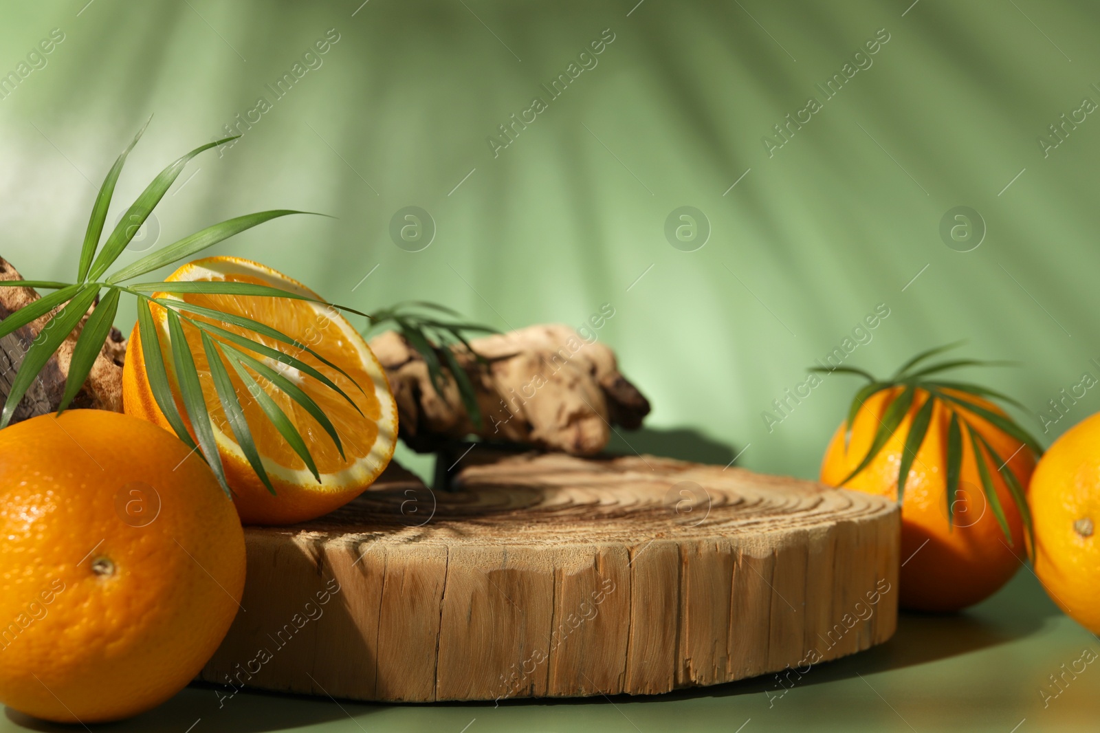 Photo of Tasty fresh oranges and leaves on green background, closeup. Space for text