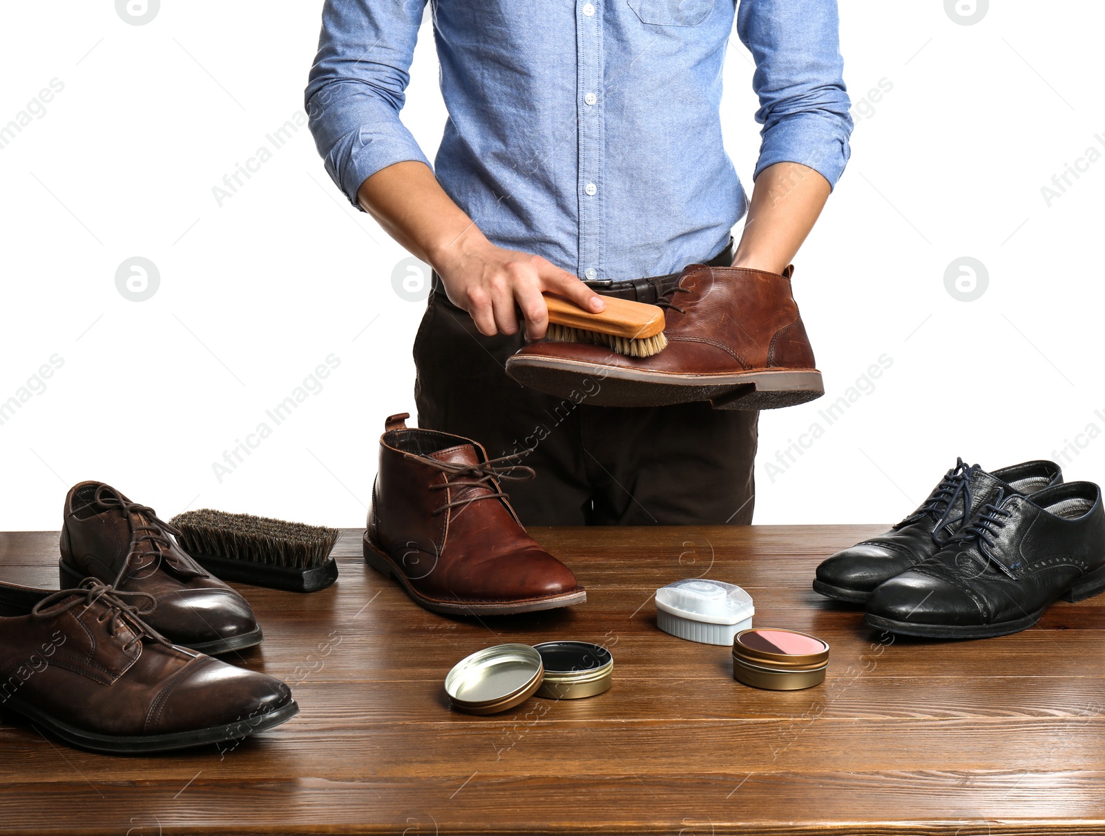 Photo of Man cleaning leather shoe at wooden table against white background, closeup