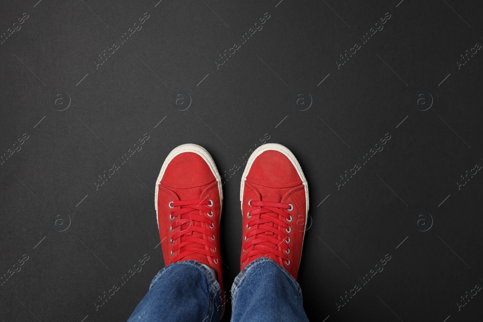 Photo of Woman in stylish sneakers on black background, top view. Space for text