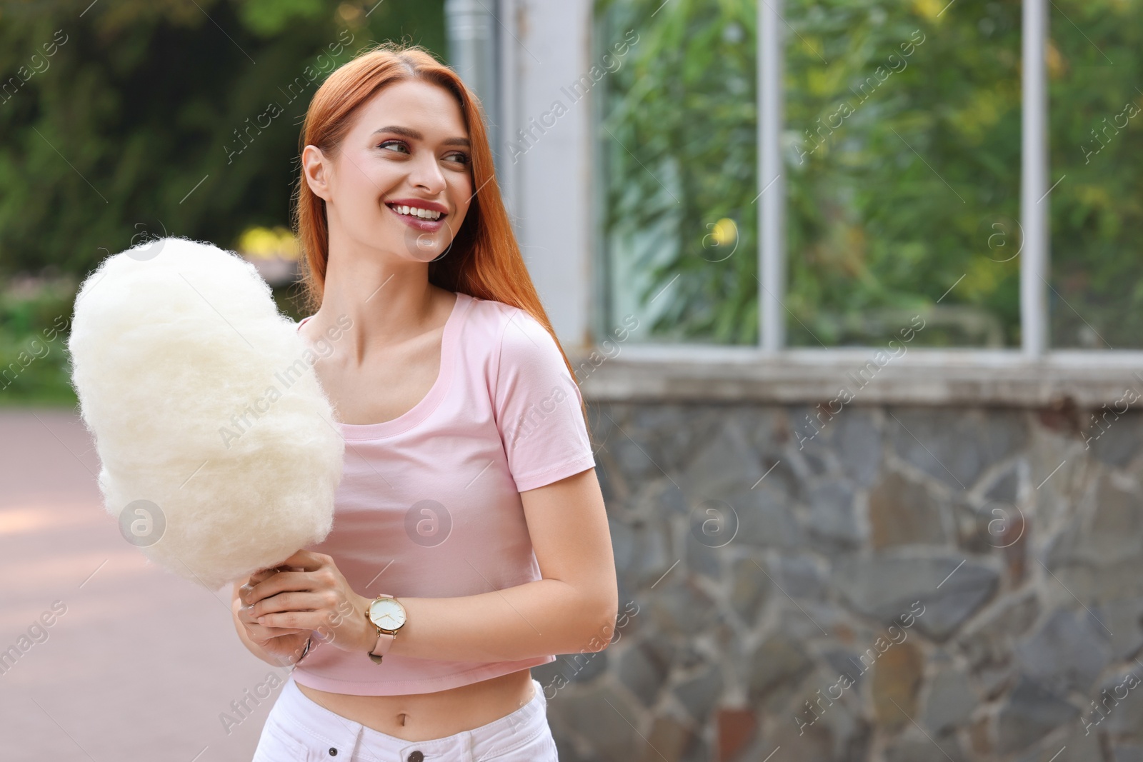 Photo of Smiling woman with cotton candy outdoors. Space for text