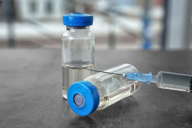 Photo of Vials and syringe with medicine on blurred background. Vaccination concept