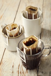 Photo of Cups with drip coffee bags on white wooden table