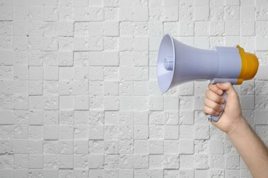 Man holding megaphone near white wall