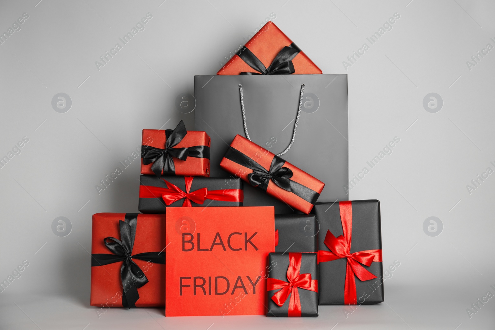 Photo of Many gifts and sheet of paper with words Black Friday on light grey background