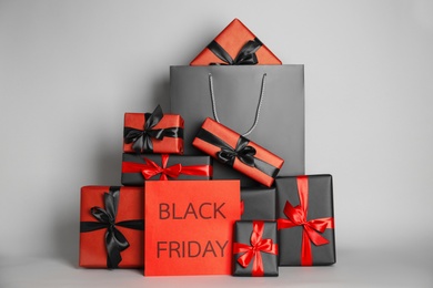 Many gifts and sheet of paper with words Black Friday on light grey background