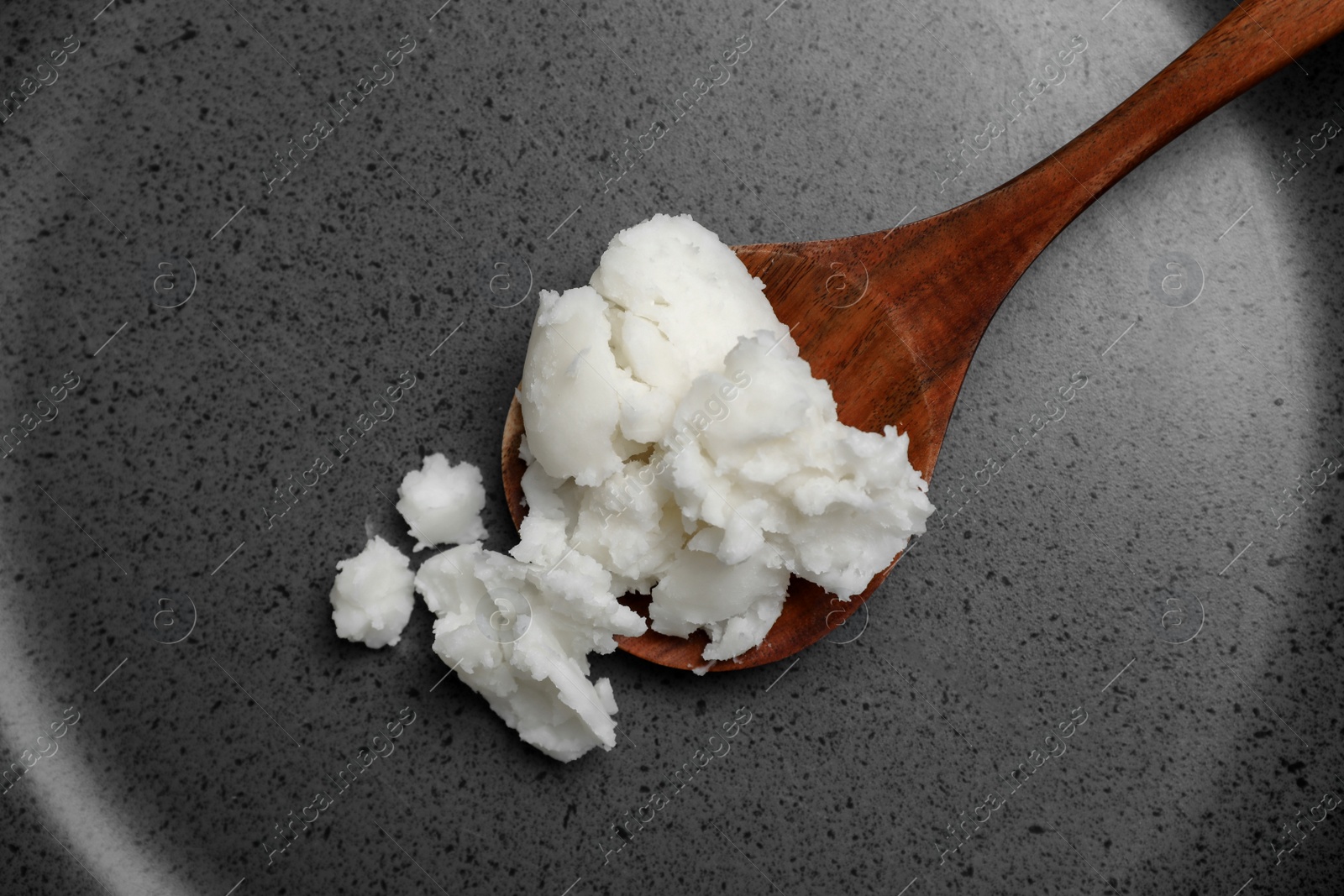 Photo of Frying pan with coconut oil and wooden spoon, closeup