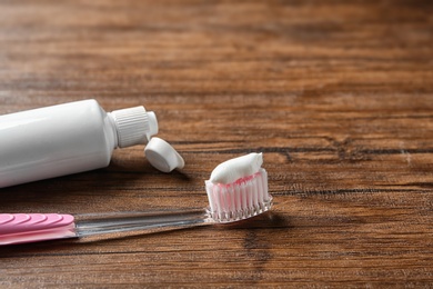 Photo of Toothbrush and tube of paste on wooden table, closeup