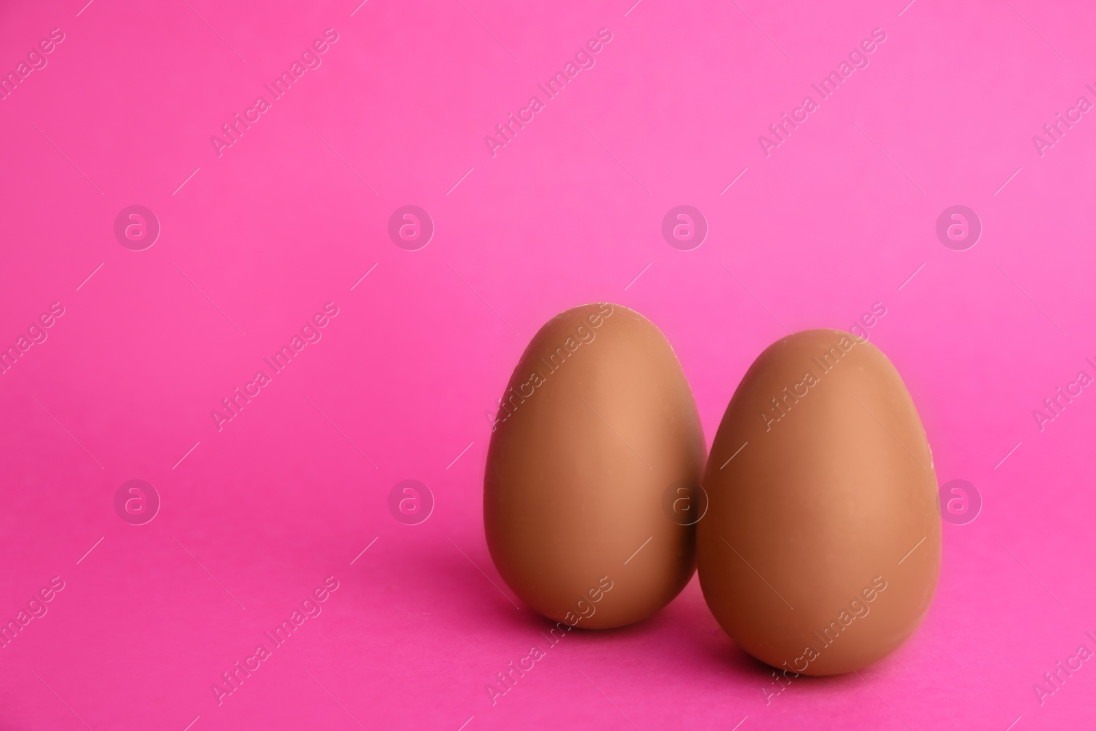 Photo of Sweet chocolate eggs on pink background. Space for text