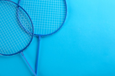 Photo of Badminton rackets on light blue background, flat lay. Space for text
