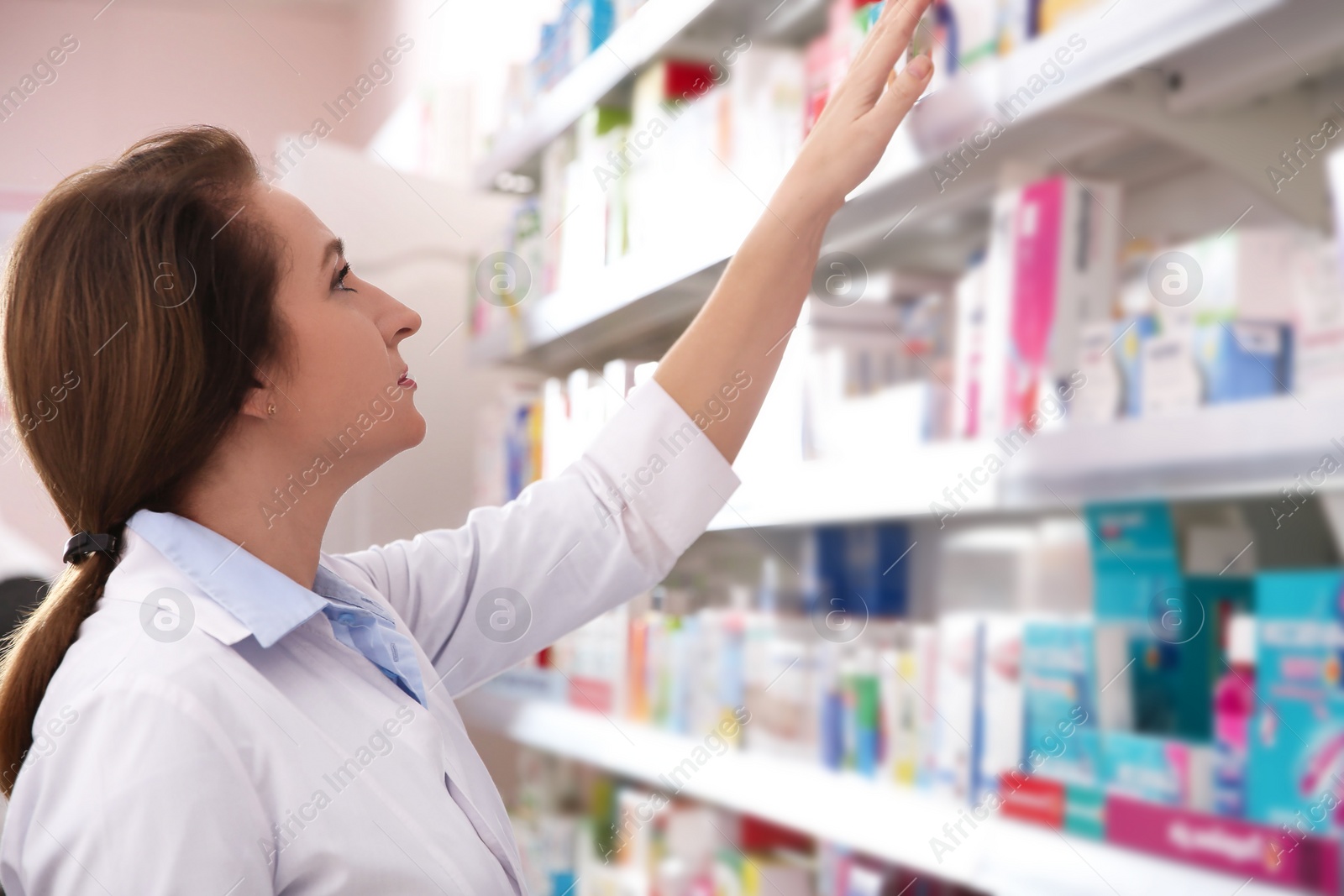 Photo of Professional pharmacist near shelves with merchandise in drugstore