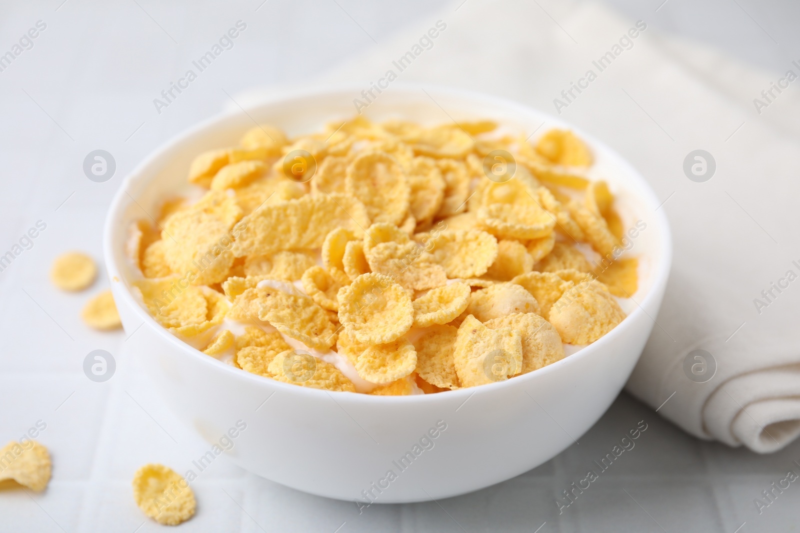 Photo of Breakfast cereal. Tasty corn flakes with milk in bowl on white table, closeup