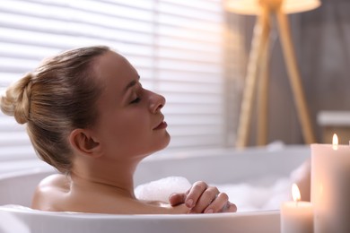 Photo of Beautiful woman taking bath in tub with foam indoors