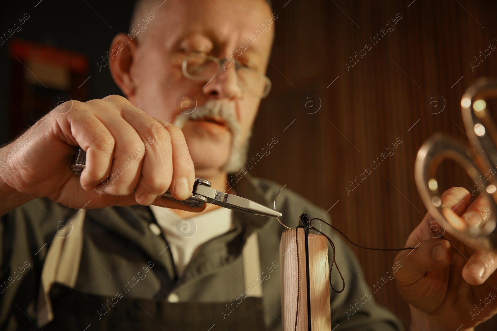 Photo of Man sewing piece of leather in workshop, closeup