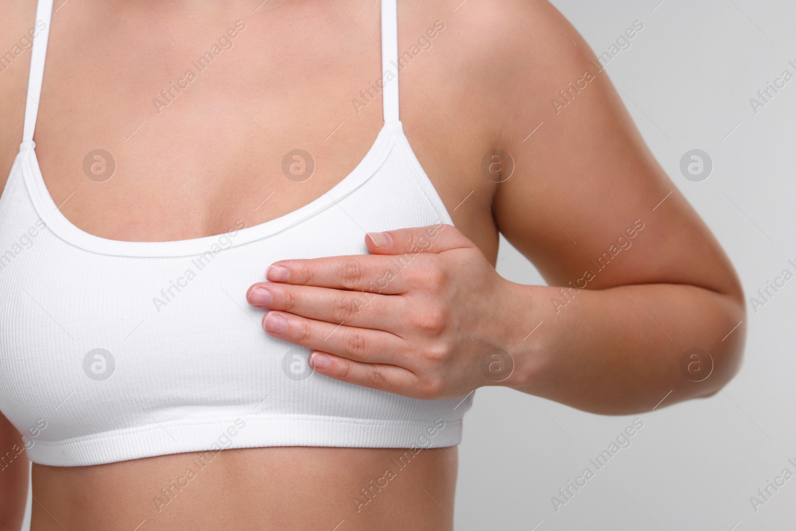 Photo of Mammology. Woman doing breast self-examination on light grey background, closeup