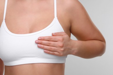 Mammology. Woman doing breast self-examination on light grey background, closeup