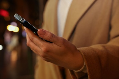 Photo of Woman using smartphone on blurred background, closeup