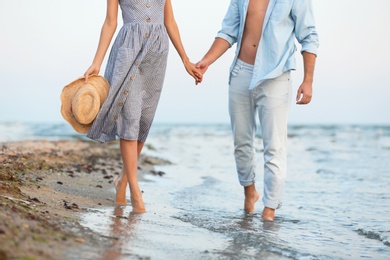 Photo of Young couple spending time together on beach, focus on legs