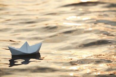 Paper boat floating on water outdoors. Space for text