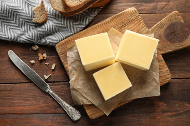 Wooden board with fresh butter and knife on table, top view