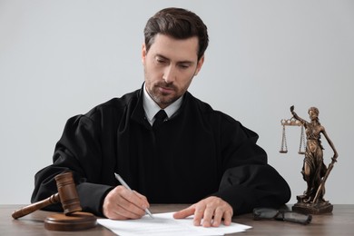 Photo of Judge working with documents at wooden table against light grey background