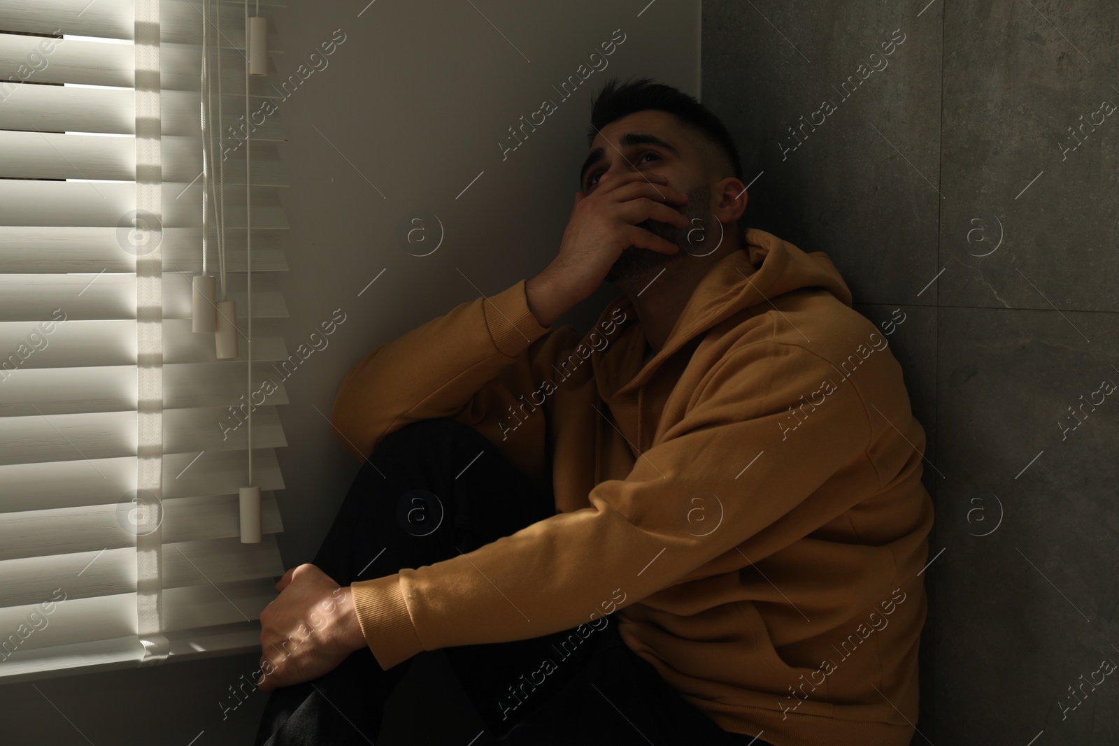 Photo of Sad man sitting near window at home