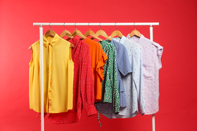 Photo of Bright clothes hanging on rack against red background. Rainbow colors