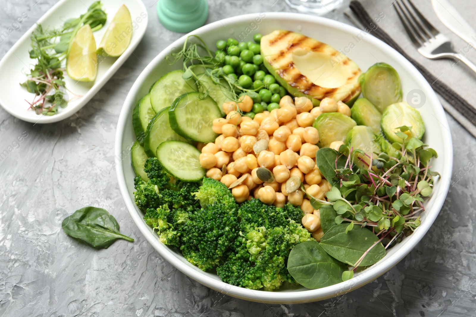 Photo of Healthy meal. Tasty vegetables and chickpeas in bowl on grey table