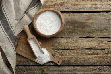 Baking powder in bowl and scoop on wooden table, flat lay. Space for text