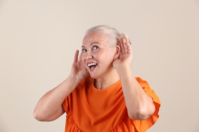 Mature woman with hearing problem on light background