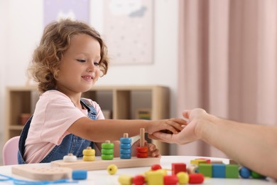 Photo of Motor skills development. Father and daughter playing with stacking and counting game at table indoors