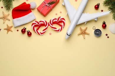 Photo of Flat lay composition with toy airplane, Santa hat and space for text on yellow background. Christmas vacation