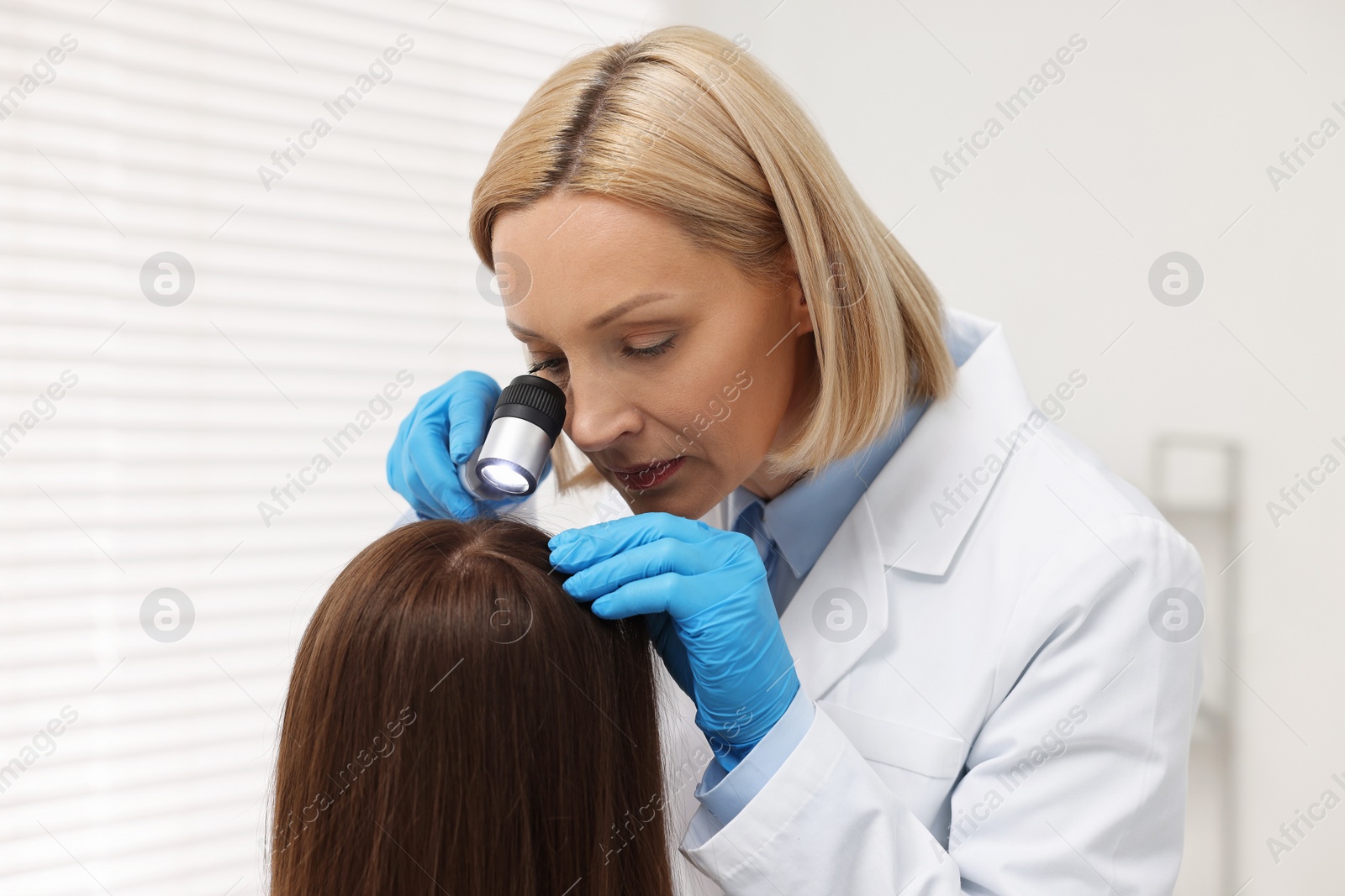 Photo of Trichologist with dermatoscope examining patient`s hair in clinic