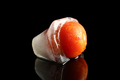 Photo of Ripe frozen tomato on dark table. Keeping vegetables fresh