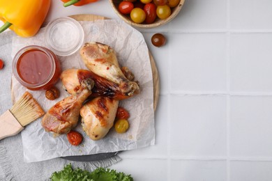 Photo of Flat lay composition with marinade and roasted chicken drumsticks on white tiled table. Space for text