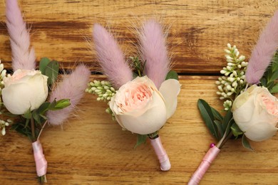 Photo of Many stylish boutonnieres on wooden table, flat lay