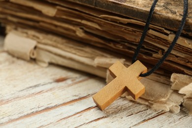 Photo of Christian cross and Bible on white wooden table, closeup