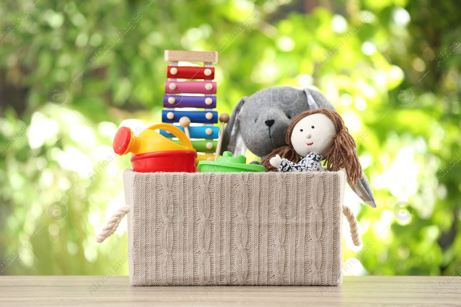 Photo of Box with different child toys on table against blurred background